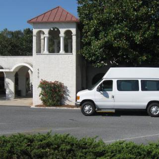 A white van parked in front of a building with distinctive architectural features.