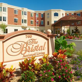 A view of an assisted living facility with landscaped gardens and clear blue skies.