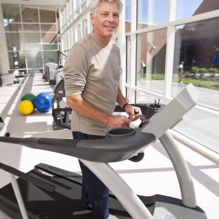 A person using a treadmill in a bright gym environment.