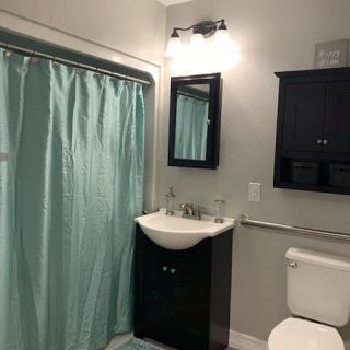 A modern bathroom with a light blue shower curtain and dark vanity.