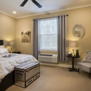 A modern bedroom with neutral colors, featuring a bed, nightstands, and stylish decor.
