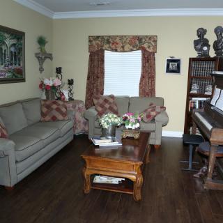 A cozy living room with a piano, sofas, and a wooden coffee table.