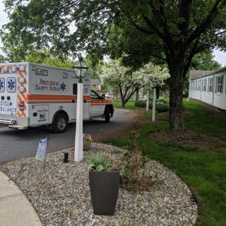An ambulance navigating through a residential area, surrounded by greenery and well-maintained landscaping.