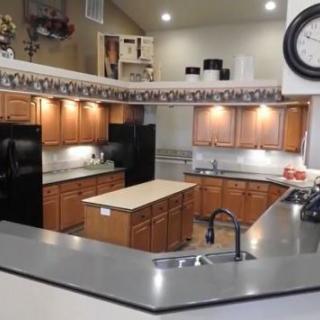 A modern kitchen interior with wooden cabinets, a central island, and black appliances.