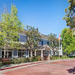 A view of a two-story building surrounded by trees under a clear blue sky.