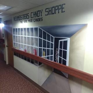 A trompe-l'oeil mural creating the illusion of a candy shop entrance in a hallway.