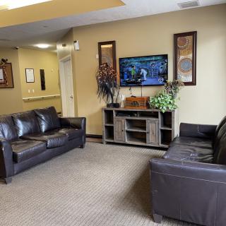 A well-furnished waiting room featuring leather sofas and a television.