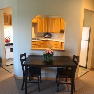 Cozy dining area with a view into the kitchen, featuring a dark wooden table and chairs.