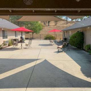 A sunny courtyard with outdoor seating, featuring red umbrellas and concrete flooring.