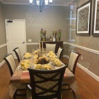 A neatly arranged dining room with a decorated table, surrounded by chairs and adorned with wall art.