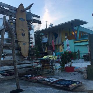 A colorful coastal building with surfboards and artwork displayed outside.