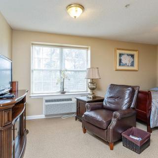 A cozy living room with a leather chair, television, and a large window letting in natural light.