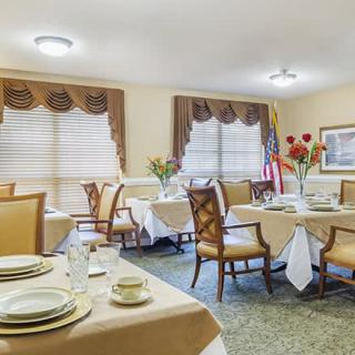 A neatly arranged dining room with tables set for a meal, featuring elegant decor and comfortable seating.