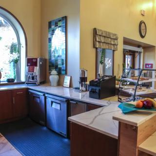 A cozy kitchen with a coffee machine and serving area near a large window.