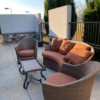 A cozy outdoor seating area with wicker furniture and cushions.