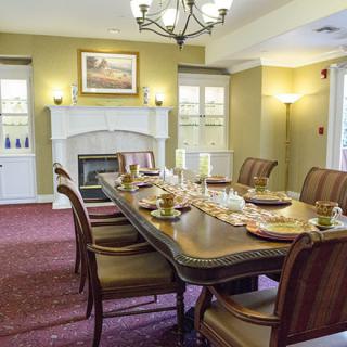 An elegantly decorated dining room with a large table set for a meal, featuring a chandelier and a fireplace.
