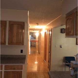 A view of a kitchen and hallway with wooden cabinets and flooring.
