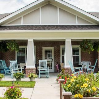 A cozy house with a welcoming porch featuring rocking chairs and a vibrant garden.