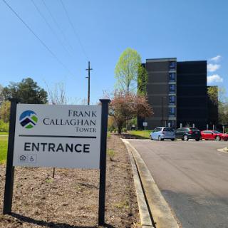 Entrance to Frank Callaghan Towers, featuring a clear blue sky and surrounding greenery.