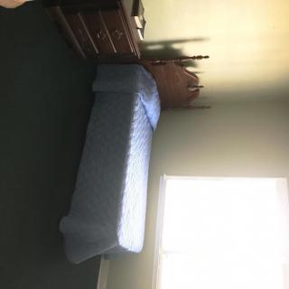 A simple bedroom with a single bed and dresser next to a window.