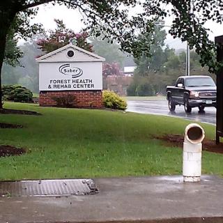 A rainy day view of a sign for a wellness center alongside a road.