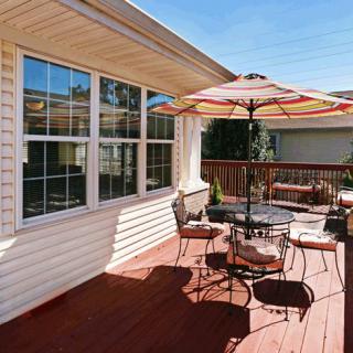 A cozy outdoor patio with a table, chairs, and an umbrella on a wooden deck.