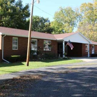 A suburban brick ranch-style house with a driveway and an American flag.