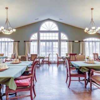 A spacious dining room with large windows and elegant chandeliers.