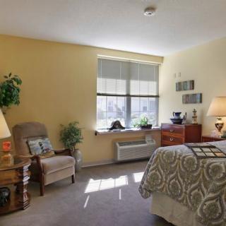 A cozy bedroom featuring a comfortable chair, well-lit interior, and tasteful decor.