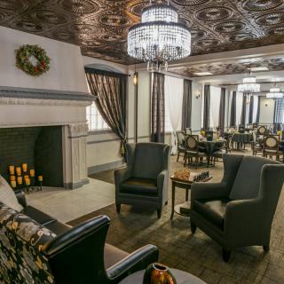 A cozy lounge area featuring elegant chandeliers, comfortable armchairs, and a decorative fireplace.