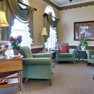 A cozy living room with comfortable chairs, decorative curtains, and soft lighting.