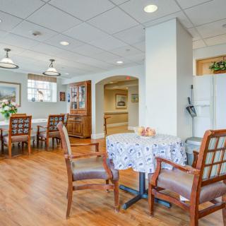 A cozy dining area with wooden floors and neatly arranged tables and chairs.