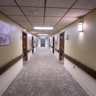 A well-lit hallway with multiple doors and carpeted flooring.