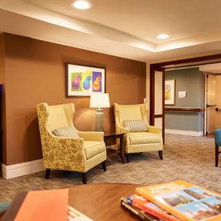 A cozy lobby area with armchairs and a lamp beneath colorful artwork on the wall.
