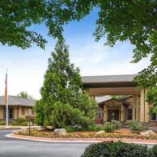A building entrance surrounded by trees and a circular driveway.