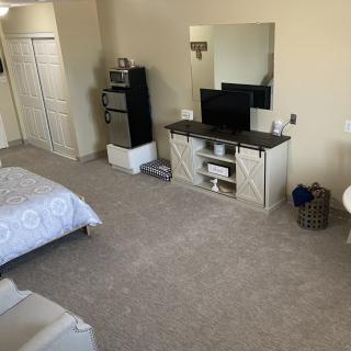 A cozy bedroom with a TV, mirror, and neatly arranged furniture.