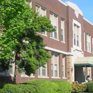 A charming brick school building surrounded by lush greenery.