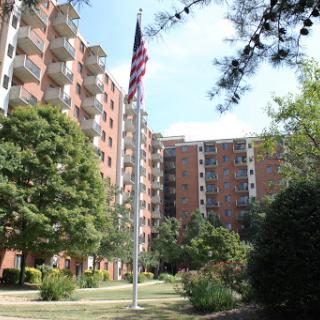 A view of residential apartments featuring a flagpole and landscaped surroundings.