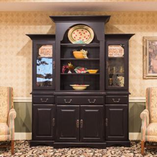 A traditional china cabinet displaying decorative dishes in a living room setting.