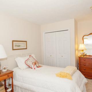 A cozy bedroom with a single bed, a wooden dresser, and a closet.