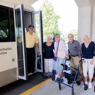 A group of elderly people standing in front of a bus.