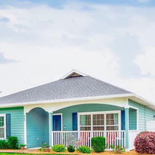 A charming blue house with a front porch and landscaped yard.