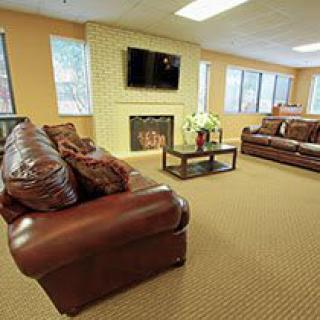 A cozy living room with leather sofas, a fireplace, and a mounted television.