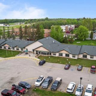 Aerial view of a building with a parking lot surrounded by trees and open sky.