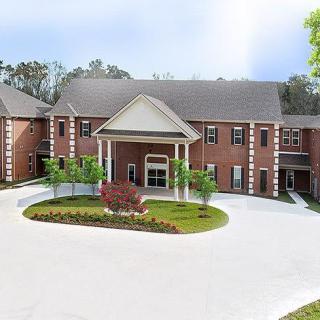 A large, brick building with a landscaped entrance and circular driveway.