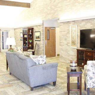 A cozy living room with a sofa, television, and bookshelf against a brick wall.
