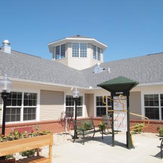 A bright and sunny courtyard featuring outdoor seating and a modern building with large windows.