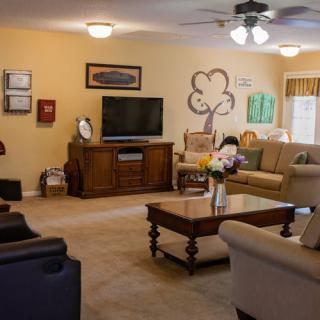 A cozy living room with sofas, a television, and a coffee table adorned with flowers.