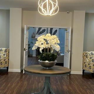 A modern interior featuring a round table with a floral arrangement and a stylish chandelier.