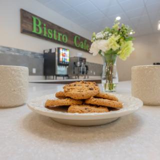 A cozy bistro setting with a plate of cookies and coffee mugs on the table.
